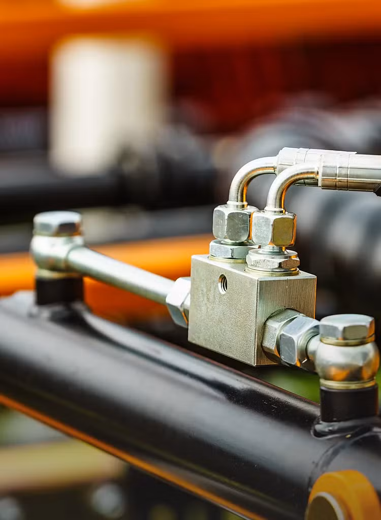 Zbliżenie na metalowe złączki i przewody instalacji hydraulicznej maszyny rolniczej